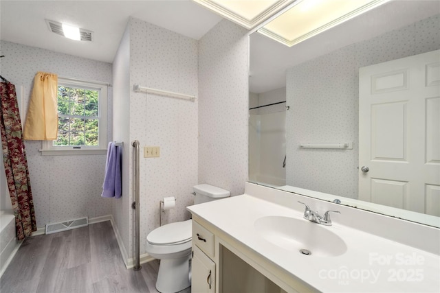 bathroom featuring visible vents, toilet, vanity, wood finished floors, and wallpapered walls