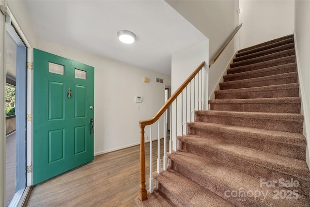 entryway featuring stairs, wood finished floors, visible vents, and baseboards