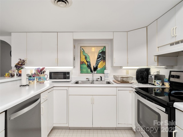 kitchen with under cabinet range hood, appliances with stainless steel finishes, light countertops, and a sink