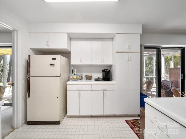 kitchen with freestanding refrigerator, light countertops, and white cabinetry