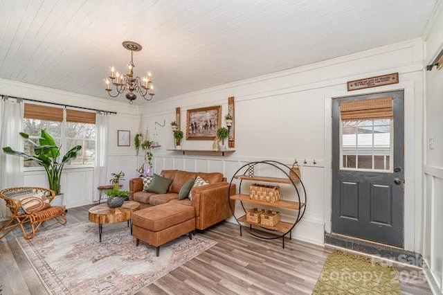 sitting room featuring crown molding, a chandelier, wood finished floors, and a decorative wall