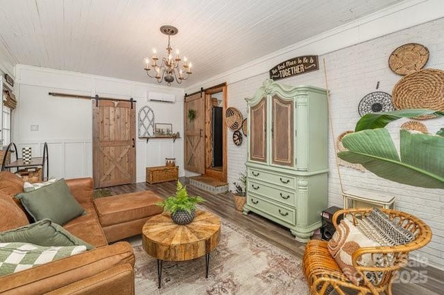 interior space with a barn door, ornamental molding, wood finished floors, and an AC wall unit