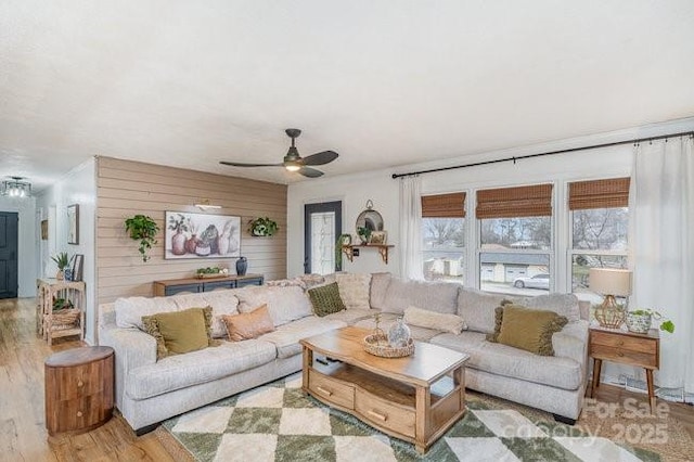 living room featuring ceiling fan, wood walls, and wood finished floors