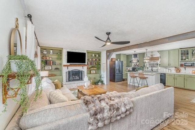 living room featuring a fireplace with raised hearth, light wood finished floors, and a ceiling fan