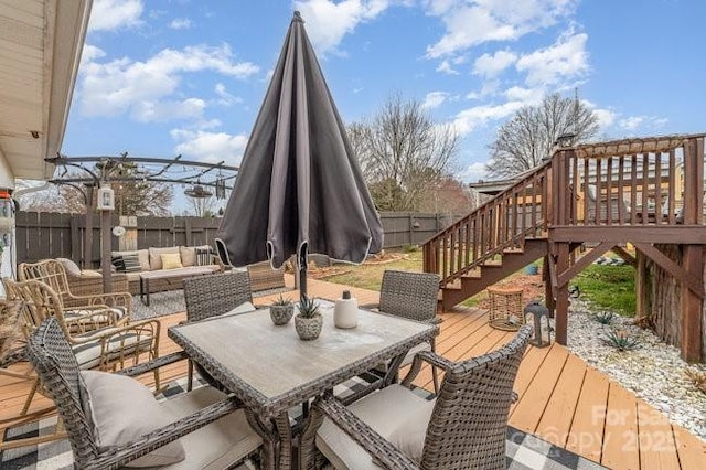 wooden deck featuring outdoor dining area, a fenced backyard, stairs, and an outdoor hangout area