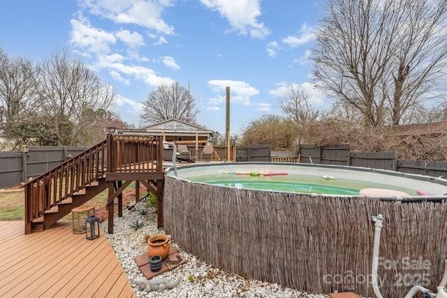 exterior space featuring a deck, stairway, a fenced backyard, and a fenced in pool