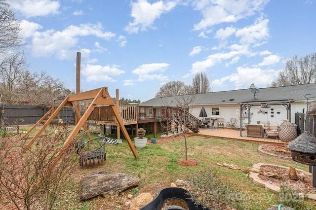 view of jungle gym featuring stairway, fence, a lawn, and a wooden deck