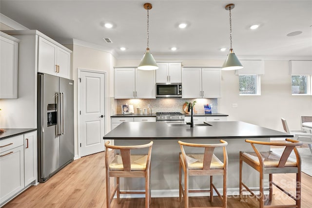 kitchen featuring white cabinetry, dark countertops, decorative light fixtures, and high quality appliances