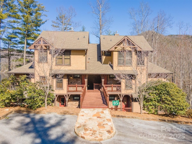 view of front of home with stairs, a deck, roof with shingles, and a chimney