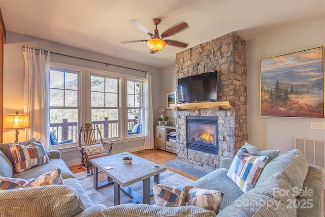 living area with ceiling fan, a fireplace, baseboards, and wood finished floors