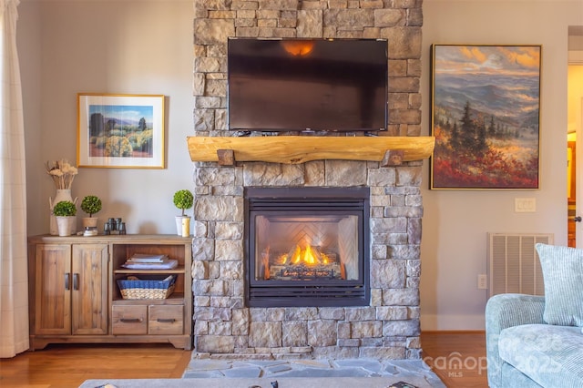 details featuring a fireplace, wood finished floors, visible vents, and baseboards