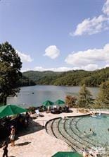 view of swimming pool featuring a water view and a patio