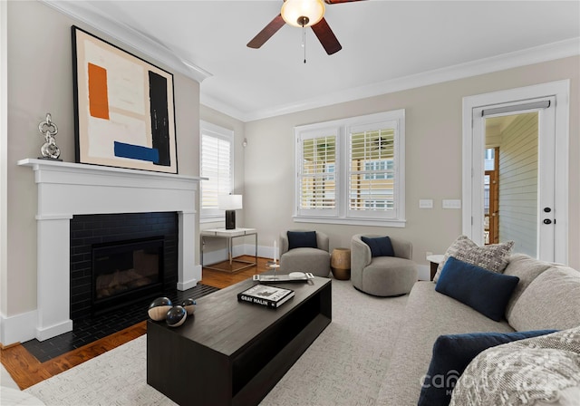 living area with baseboards, a brick fireplace, dark wood finished floors, and crown molding