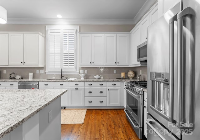 kitchen featuring a sink, ornamental molding, dark wood-type flooring, white cabinets, and stainless steel appliances