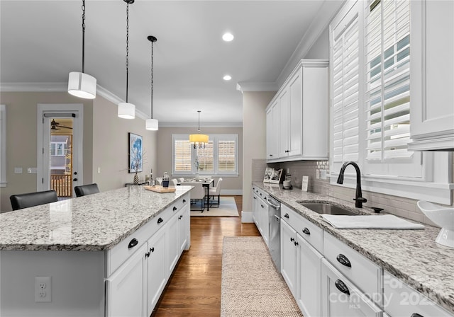 kitchen featuring a sink, dark wood finished floors, a center island, crown molding, and decorative backsplash