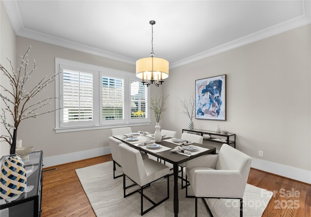 dining area with a chandelier, baseboards, crown molding, and light wood-style floors