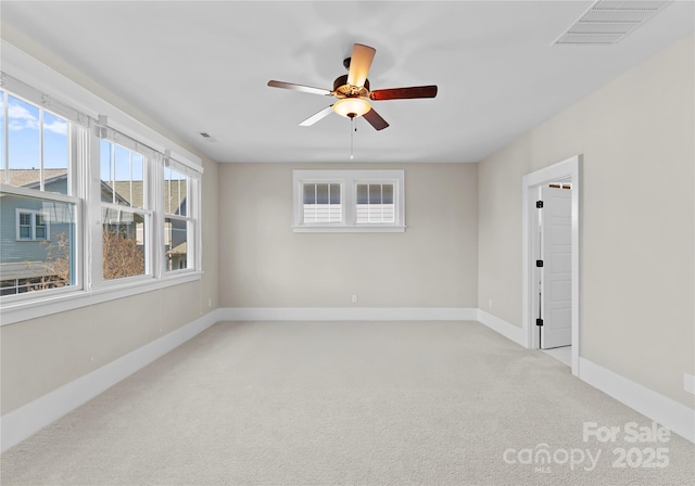 carpeted empty room featuring visible vents, baseboards, and ceiling fan