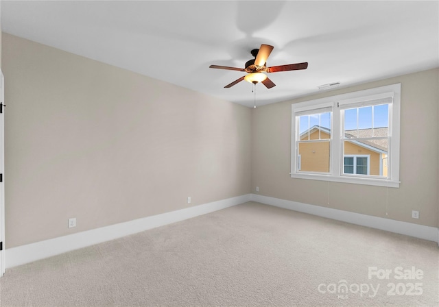 spare room with light carpet, visible vents, a ceiling fan, and baseboards