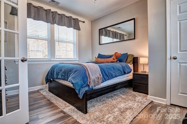 bedroom featuring baseboards, visible vents, and wood finished floors