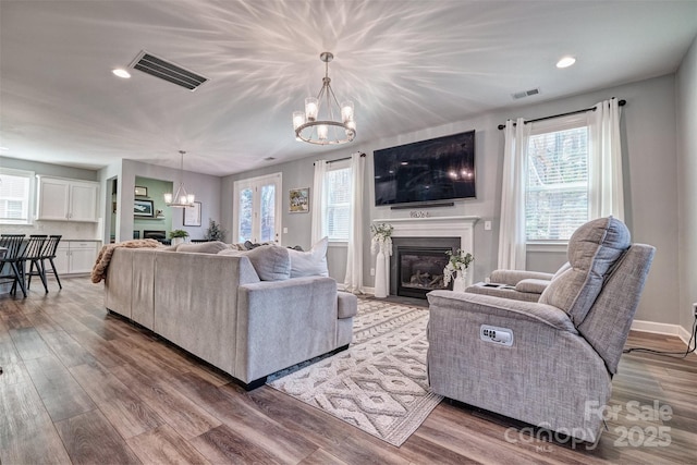 living area featuring visible vents, a fireplace, and a notable chandelier