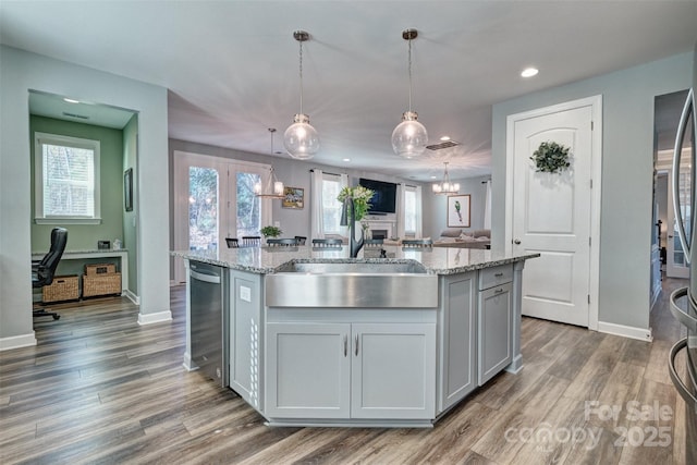 kitchen with decorative light fixtures, a center island with sink, open floor plan, light stone countertops, and dishwasher