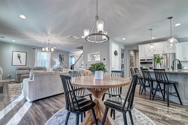 dining room featuring dark wood-type flooring, stairway, recessed lighting, and a notable chandelier