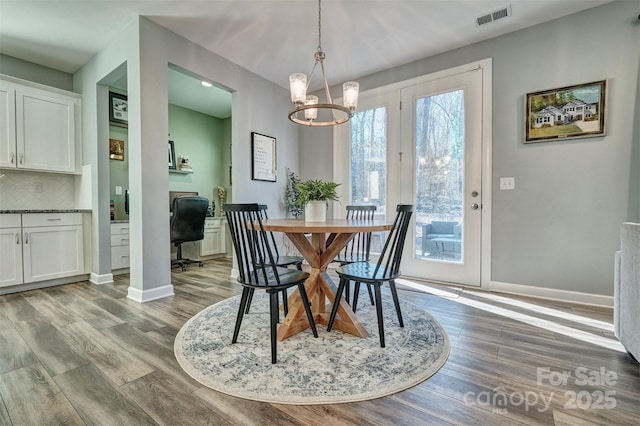 dining room featuring light wood finished floors, baseboards, visible vents, and a chandelier