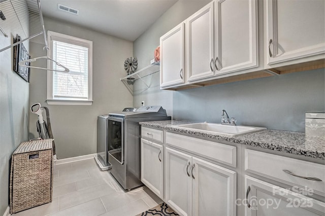 laundry room featuring washer and clothes dryer, light tile patterned floors, visible vents, cabinet space, and a sink