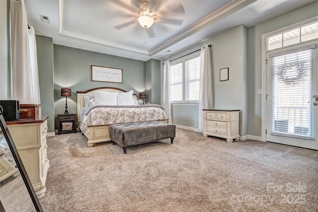 bedroom featuring a tray ceiling, light colored carpet, visible vents, and access to exterior