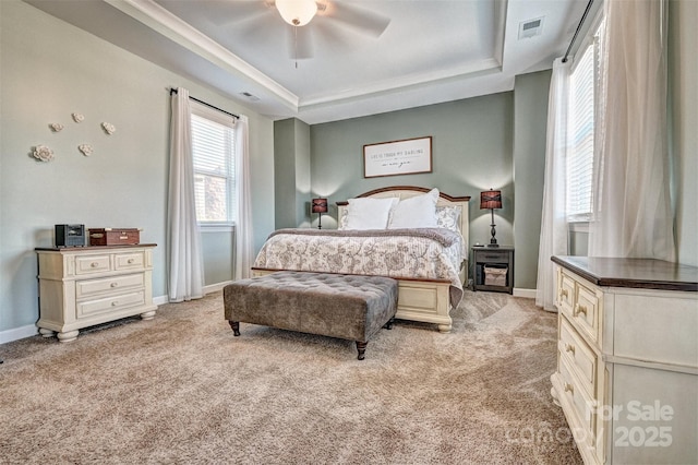 bedroom featuring light carpet, visible vents, a tray ceiling, and baseboards