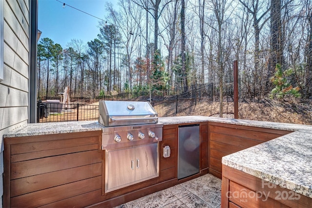 view of patio with an outdoor kitchen, fence, and a grill