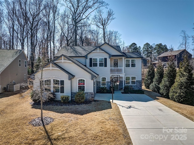 view of front of home featuring stone siding, a front yard, and driveway