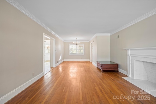 unfurnished living room featuring an inviting chandelier, crown molding, a fireplace, and wood finished floors