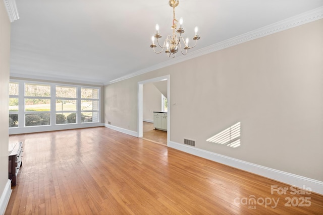 unfurnished living room featuring baseboards, visible vents, an inviting chandelier, crown molding, and light wood-type flooring