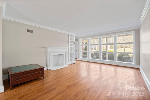 unfurnished living room featuring crown molding, a fireplace, wood-type flooring, visible vents, and baseboards