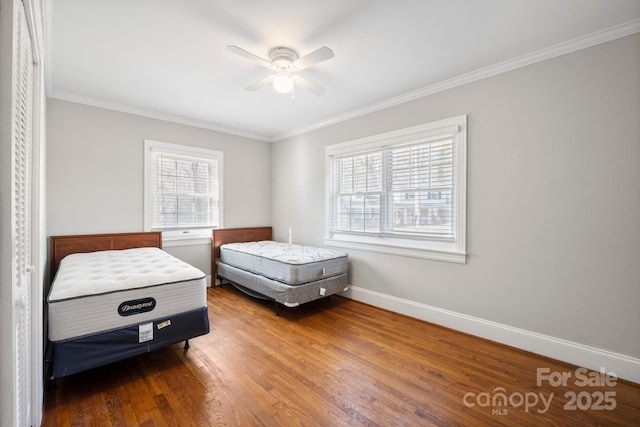 bedroom featuring multiple windows, crown molding, baseboards, and wood finished floors