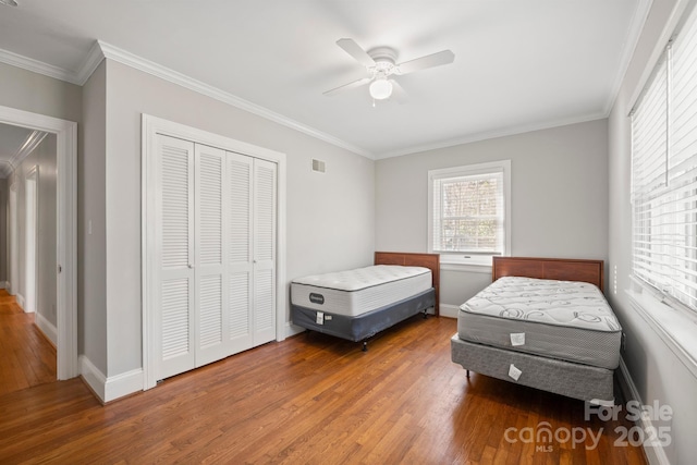 bedroom featuring ornamental molding, a closet, wood finished floors, and visible vents