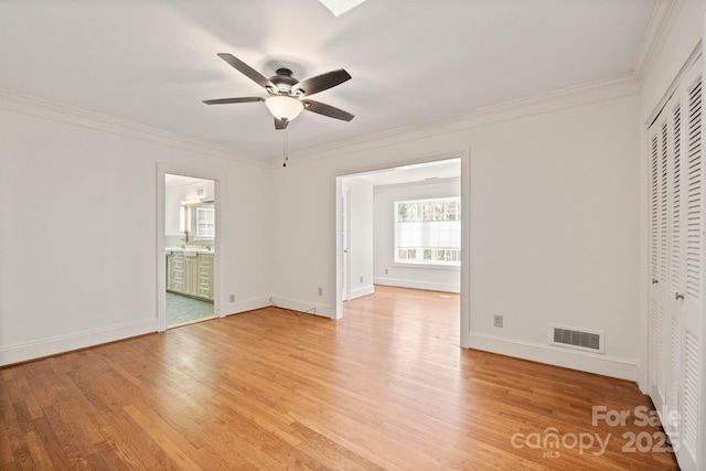 spare room with light wood-style flooring, visible vents, baseboards, and ornamental molding