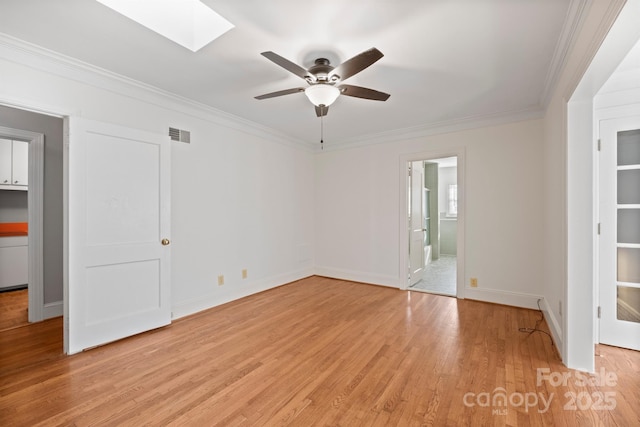 unfurnished room with a skylight, visible vents, ceiling fan, crown molding, and light wood-type flooring