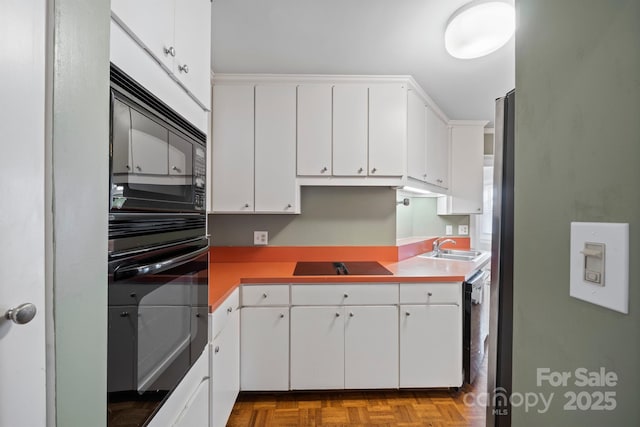 kitchen featuring white cabinetry, a sink, and black appliances