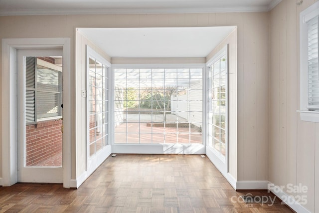 entryway featuring baseboards, a sunroom, and crown molding