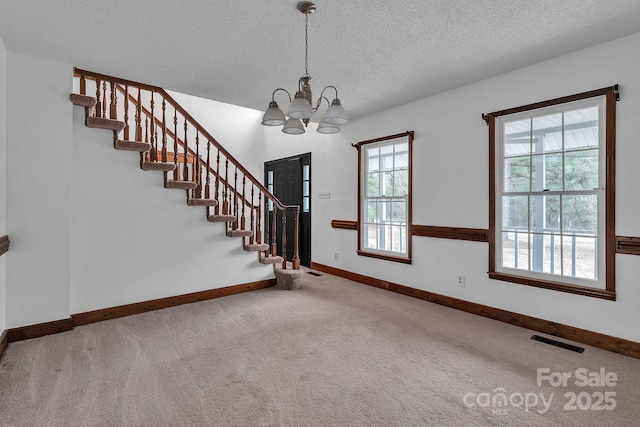 interior space featuring stairway, carpet, visible vents, an inviting chandelier, and a textured ceiling