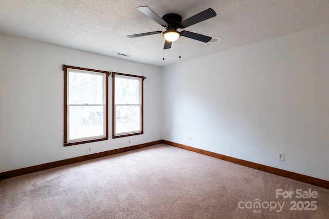 carpeted spare room featuring a ceiling fan, baseboards, visible vents, and a textured ceiling