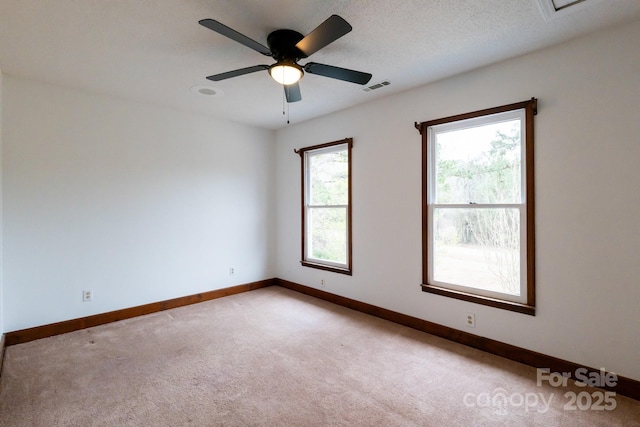 unfurnished room with visible vents, baseboards, light carpet, a textured ceiling, and a ceiling fan