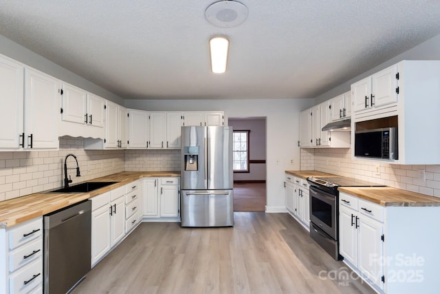 kitchen featuring appliances with stainless steel finishes, wooden counters, light wood-style floors, and a sink