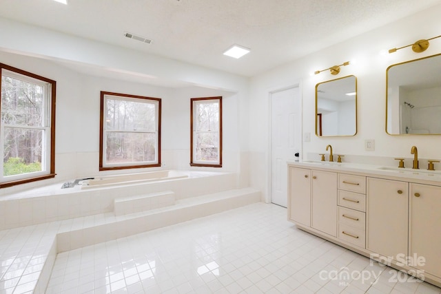 bathroom featuring visible vents, a garden tub, double vanity, tile patterned floors, and a sink