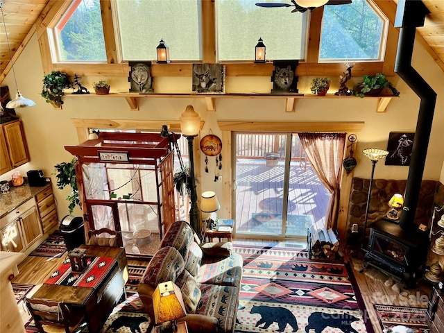 living room with a wood stove, plenty of natural light, ceiling fan, and wood finished floors