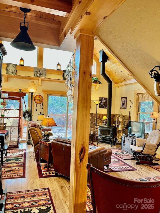 living room featuring lofted ceiling with beams, wood finished floors, and a wood stove