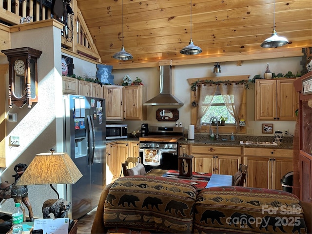 kitchen featuring wall chimney exhaust hood, appliances with stainless steel finishes, a sink, and pendant lighting