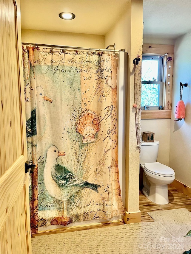 full bathroom featuring baseboards, wood finished floors, toilet, and a shower with curtain